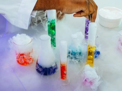 Colorful liquid in test tubes with a hand holding a container, on a white background
